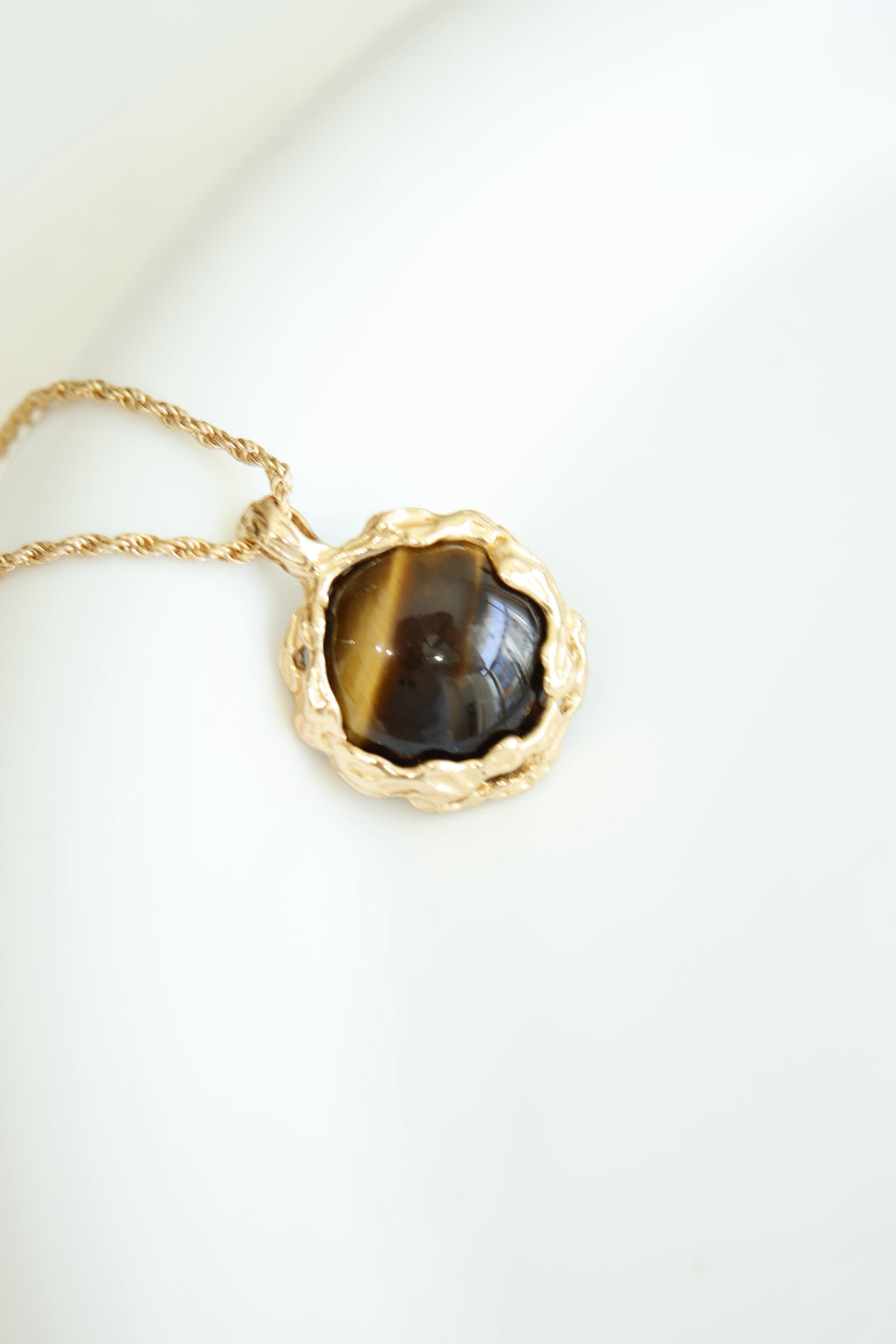 Hand-carved tiger's eye stone pendant with volcanic lava texture