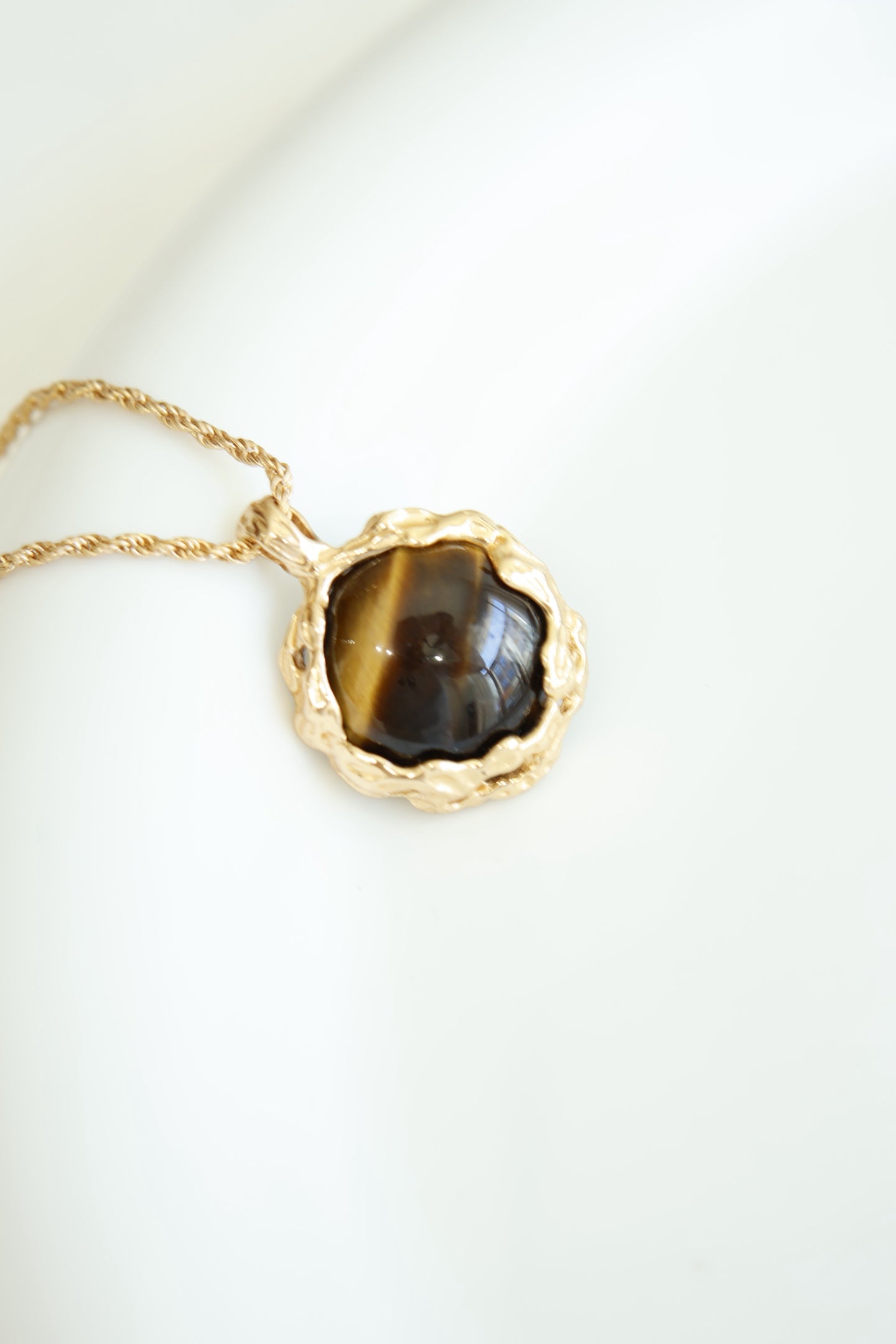 Hand-carved tiger's eye stone pendant with volcanic lava texture